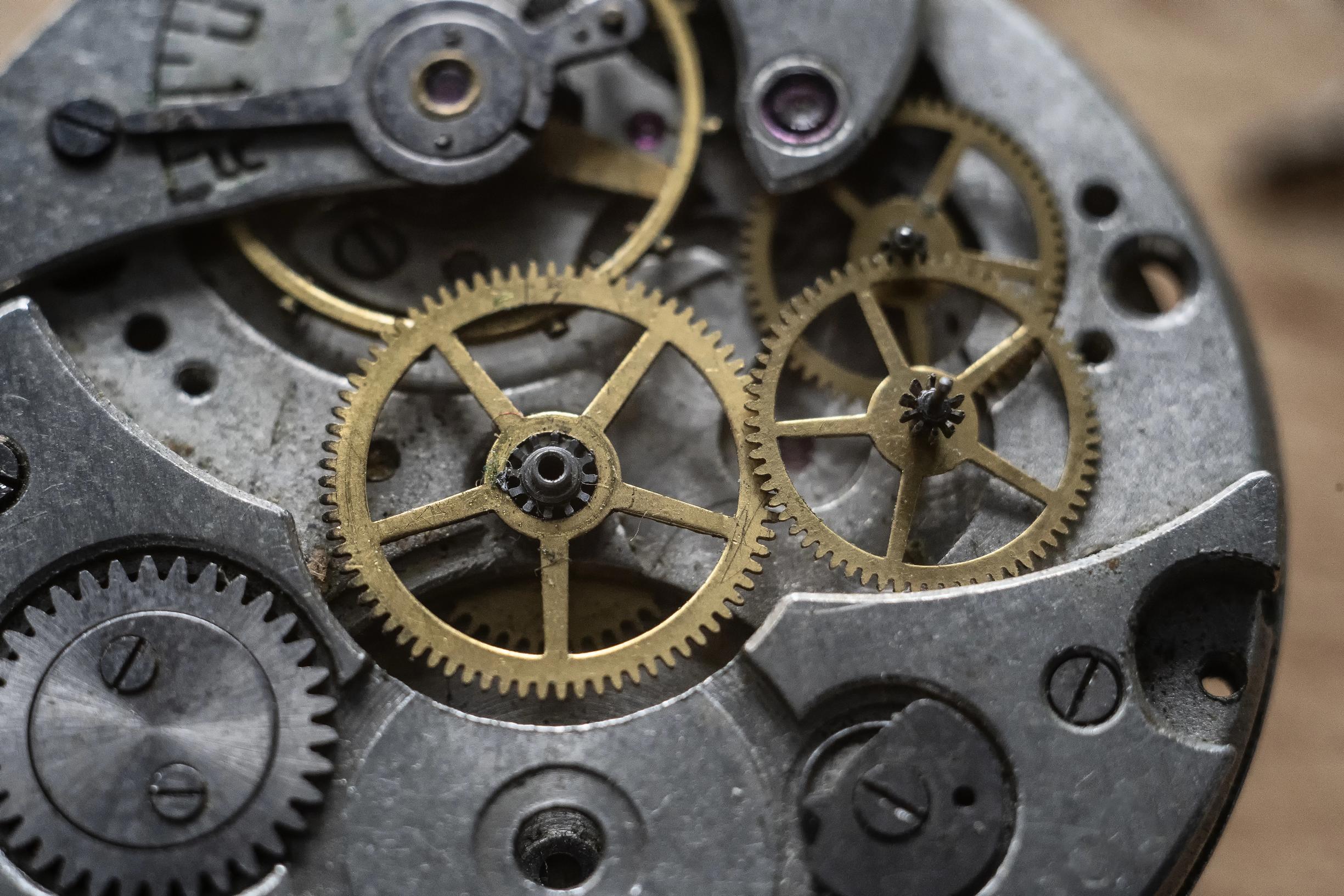 Nahaufnahme eines geöffneten mechanischen Uhrwerks mit goldenen, ineinandergreifenden Zahnrädern