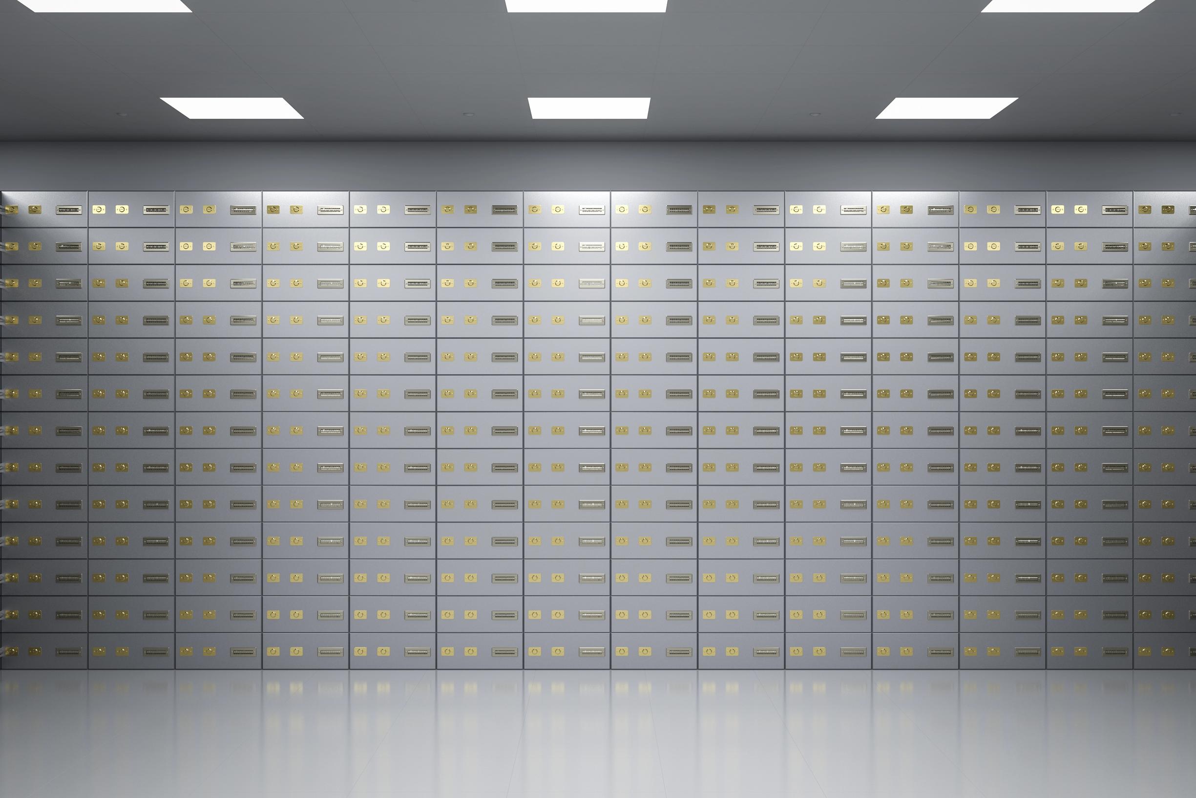 Eine Wand mit grauen Bankschliessfächern mit goldenen Schlössern – ordentlich nach aussen, ohne Hinweis auf den Inhalt dahinter.